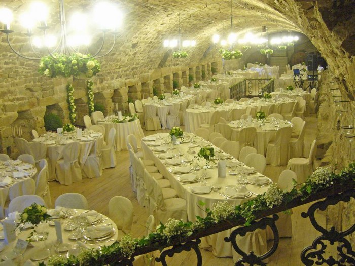 Cena di matrimonio nella Scuderia Varano. Dieci ghirlande di ortensie verdi e rose bianche sono appese ai lampadari